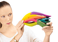A woman evaluates a multi-colored 3D printed helmet
